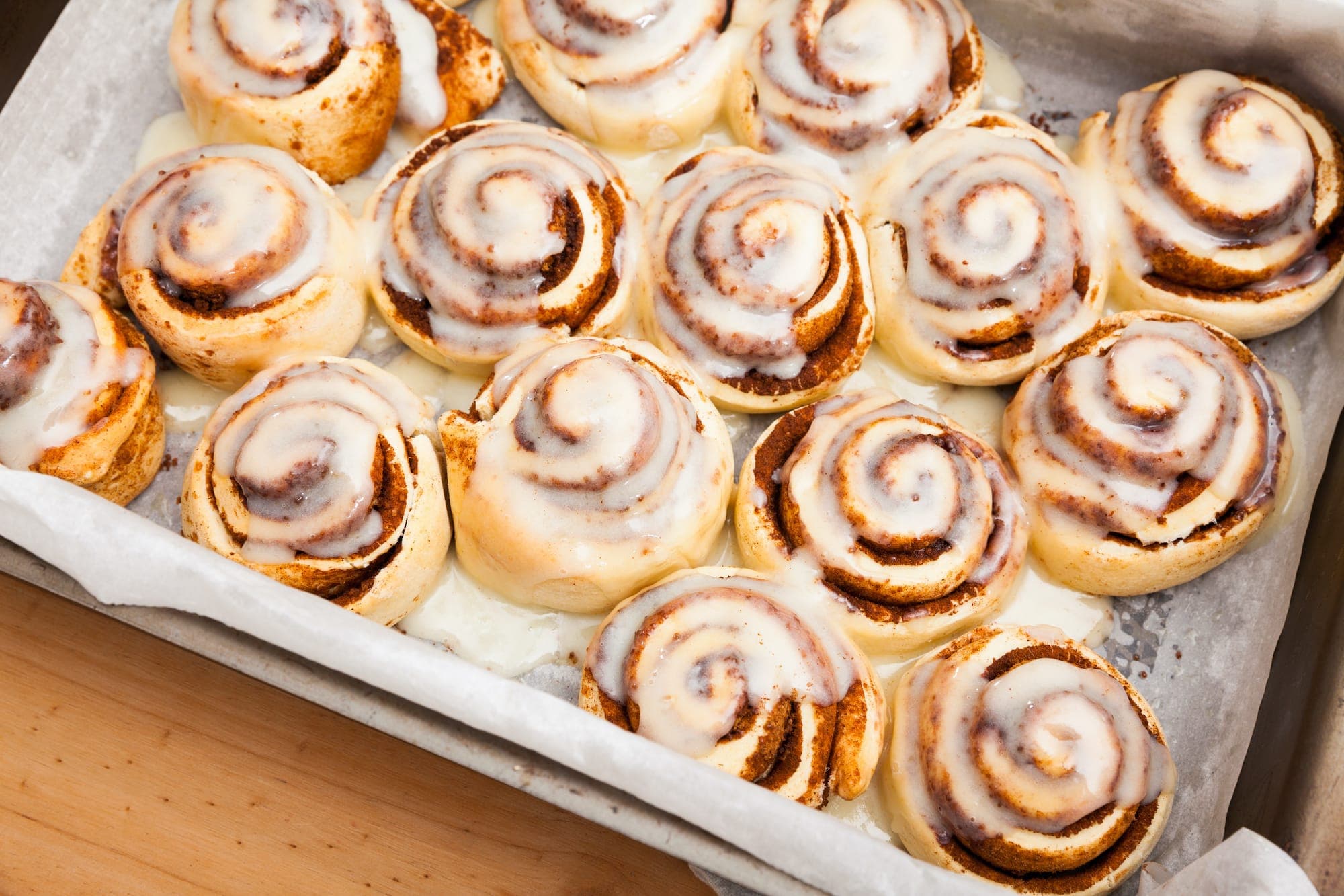 A tray of freshly baked cinnamon rolls drizzled with icing. A tray of freshly baked cinnamon rolls drizzled with icing.