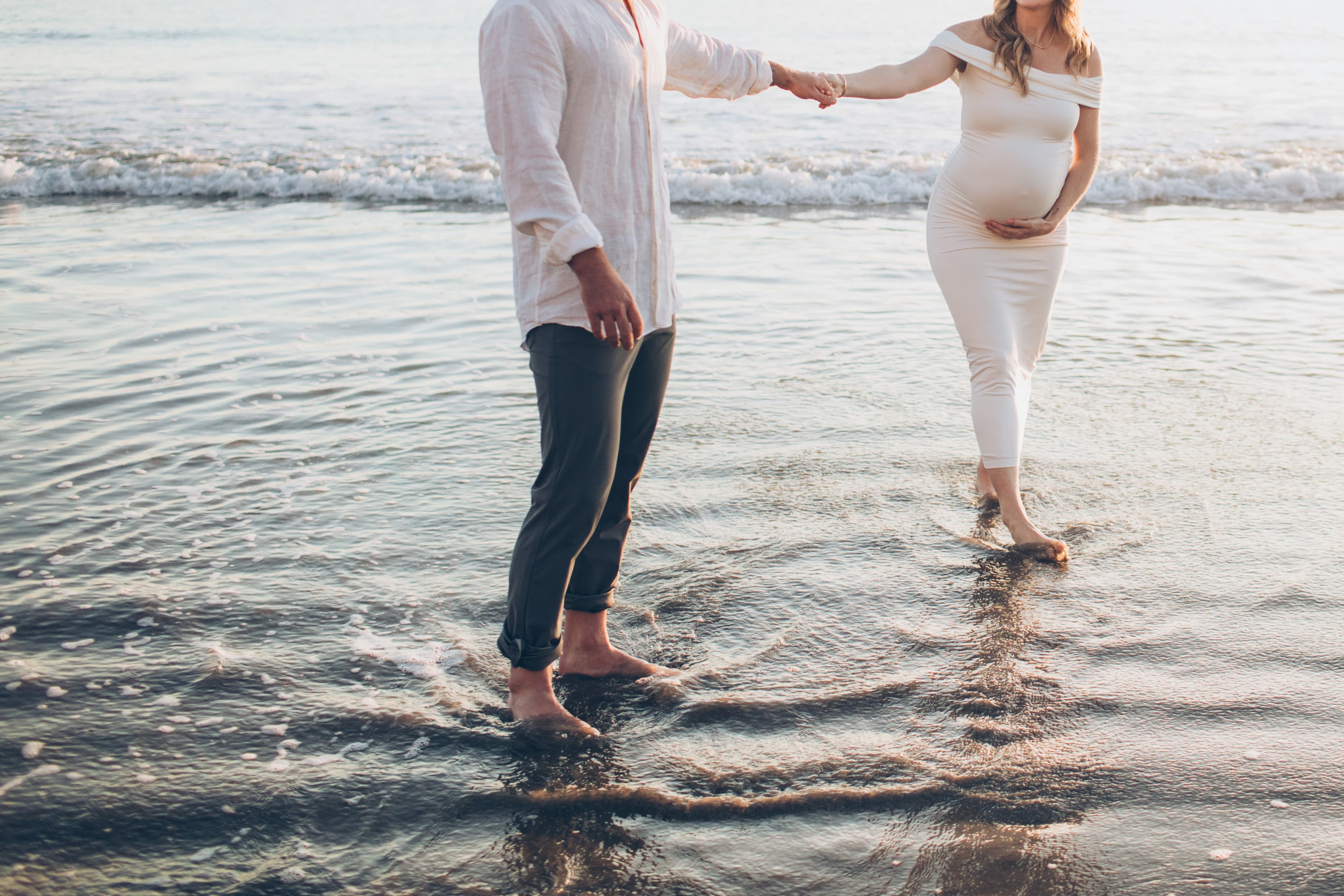 Men and a pregnant women holding hands at the beach Men and a pregnant women holding hands at the beach